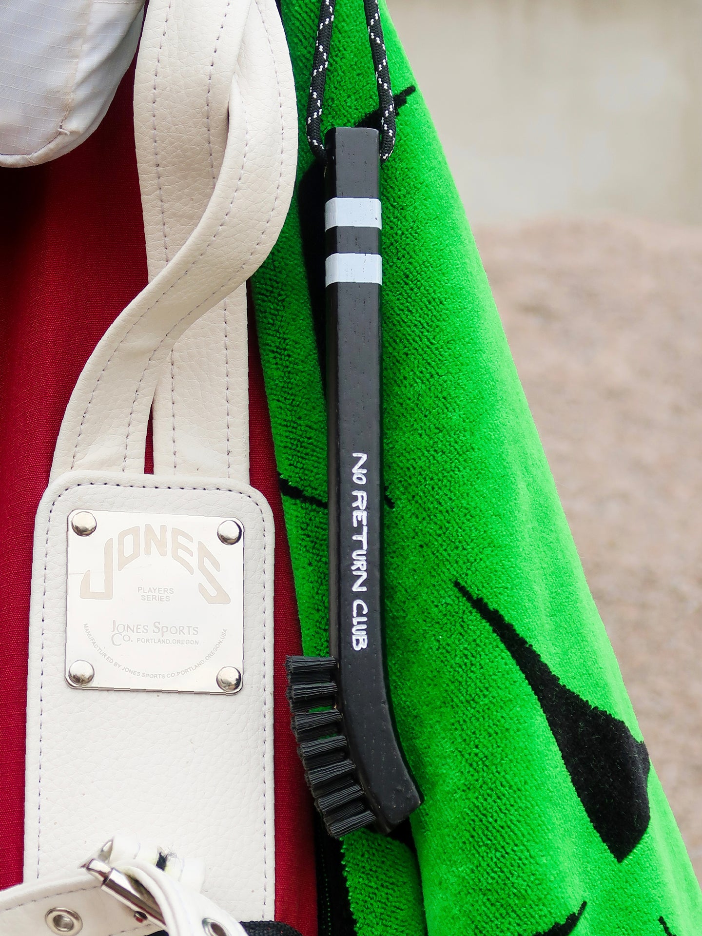 Golf club groove cleaning brush featuring speckled rope and secure bag-clip carabiner.