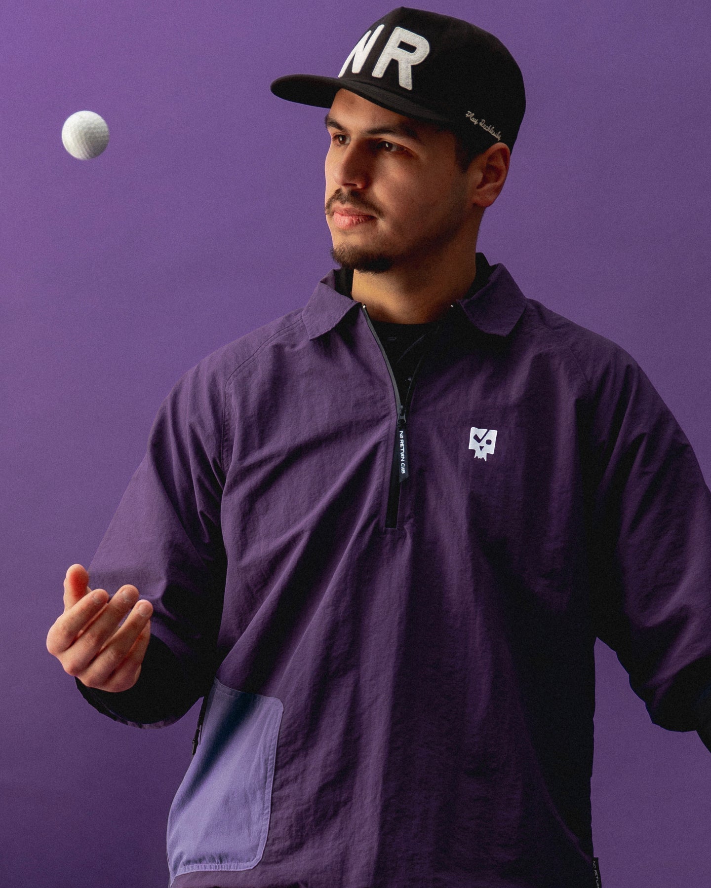 Man wearing a purple jacket and black cap with 'WR' logo on a purple background
